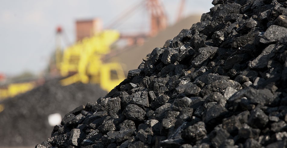 Close up of coal mound with industrial machinery in background (methane)