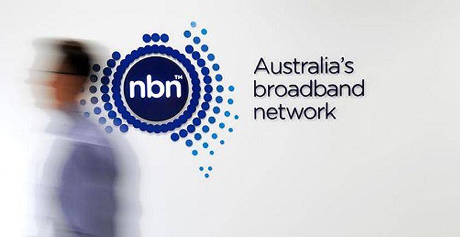 NBN Co logo on wall with blurred image of male walking past it (AGL)