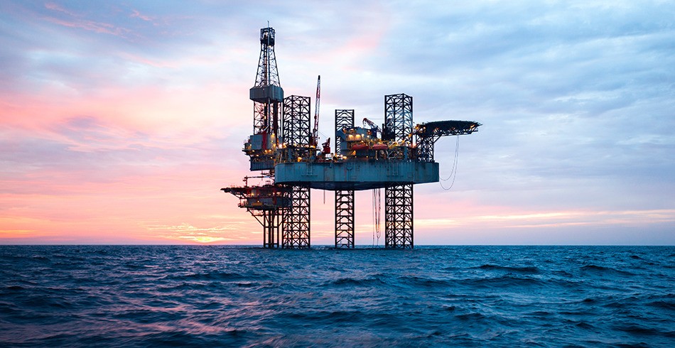 Offshore gas drilling rig in the ocean with beautiful pink and blue sunset behind it (merger)