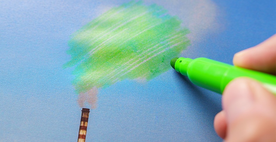 Hand uses green marker to colour in smoke pouring from chimney (environmental claims)
