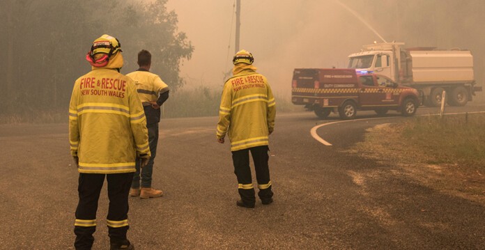 Fire and rescue personnel standing in hazy surrounds near bushfire (resilient)