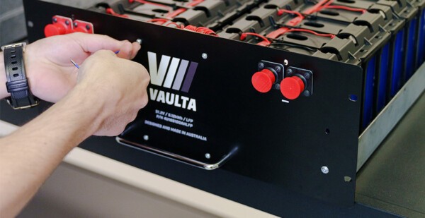 Close-up shot of a pair of hands working on a Vaulta battery (investment)
