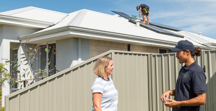 Plico solar installers talk to female homeowner while installing solar panels on the roof of the home (demand)