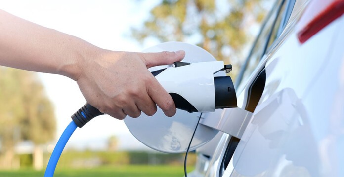 Person's hand plugging charger into electric vehicle (consumer energy)