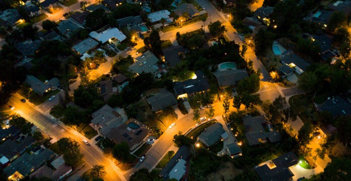 Aerial photo of a suburb lit by streetlights at night (GenCost)