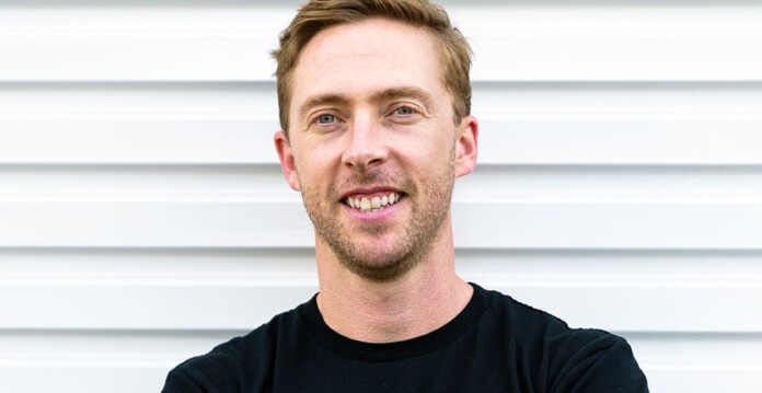 Close-up headshot of blonde, white man smiling and wearing black shirt (Vaulta)