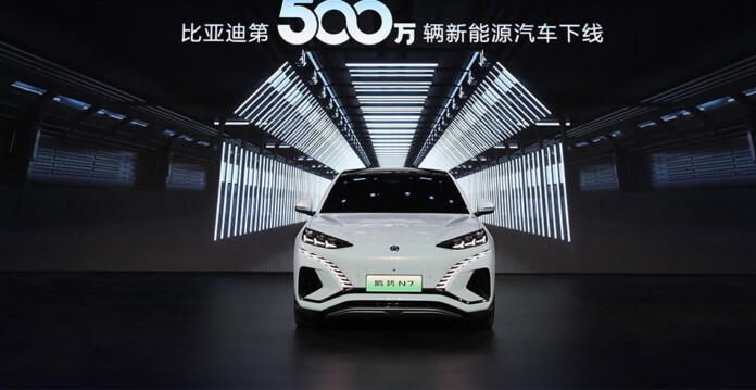 White BYD electric vehicle in front of 5 millionth celebration signage in Chinese characters (EV)
