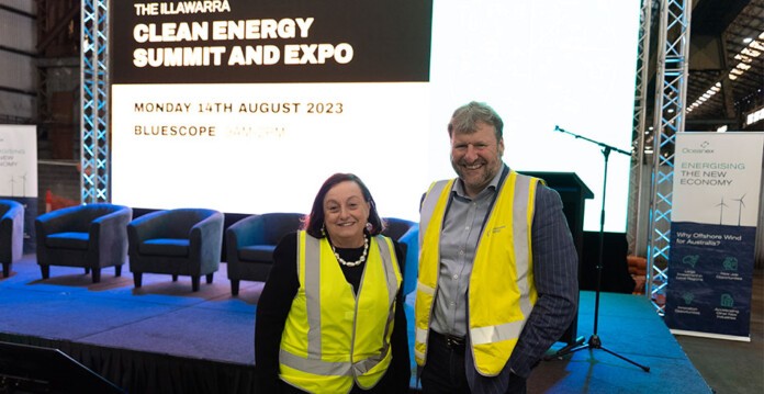 Middle-aged woman and man wearing high-vis vests standing in front of conference projector signage (endeavour wollongong)