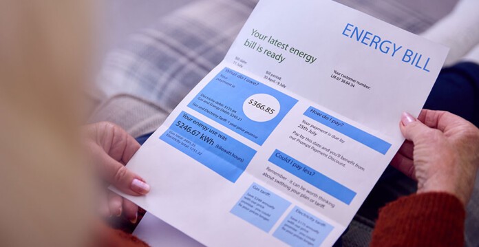 Woman with blonde hair reads paper energy bill (website)