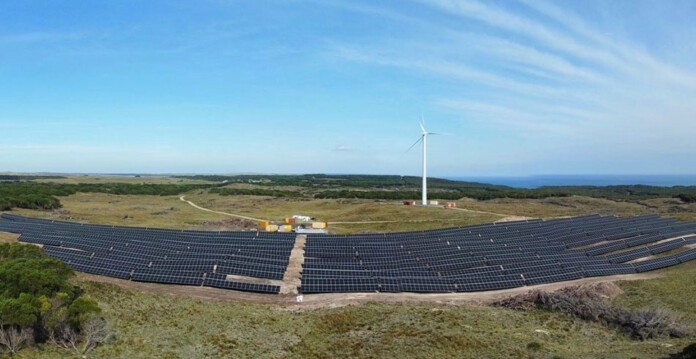 Aerial shot of solar farm on Tasmania's King Island with wind turbine in the background