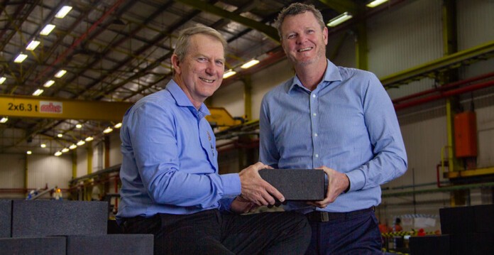 Two men in blue shirts hold thermal energy storage block (MGA Thermal)