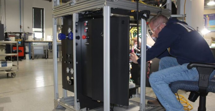 Man in blue jeans works on hydrolyser componentry in Advanced Ionics lab