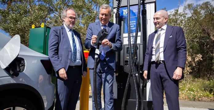 Three men wearing suits stand in front of new EV fast charger while smiling (WA EV network)