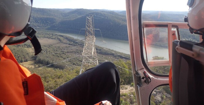 Transgrid inspections workers in a helicopter over transmission lines and towers
