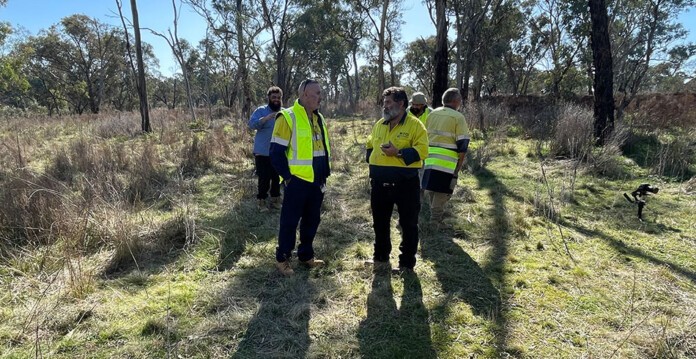 Men wearing high-vis clothing gather in bushland area in New South Wales