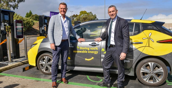 Two men wearing business attire stand smiling next to EV charging at Flinders University (v2g)
