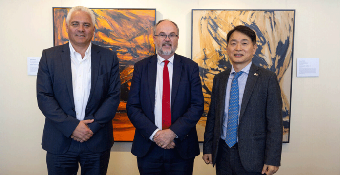 Three men in suits smiling with artwork behind them (ENGIE POSCO)