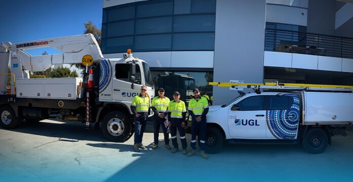 UGL service vehicles with workers dressed in high-vis clothing smiling (power)