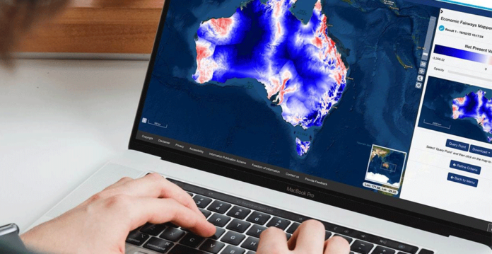 Hand typing on laptop with interactive map tool of Australia on screen
