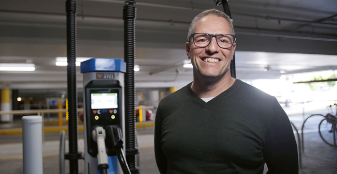 Smiling man with glasses in front of Chargefox EV charger