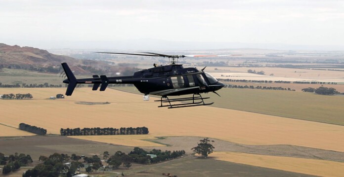 Black helicopter flying over rural land conducting aerial inspections (powercor skies)
