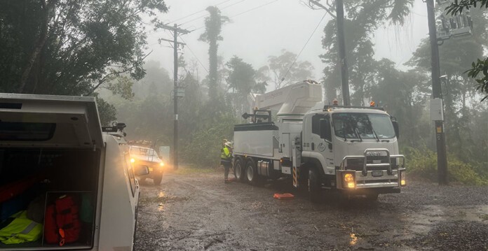 Ergon Energy crew trucks in heavy rainfall underneath vegetation and powerlines