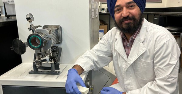 Male researcher wears turban, lab coat and blue nitrile gloves in laboratory with equipment (hair)